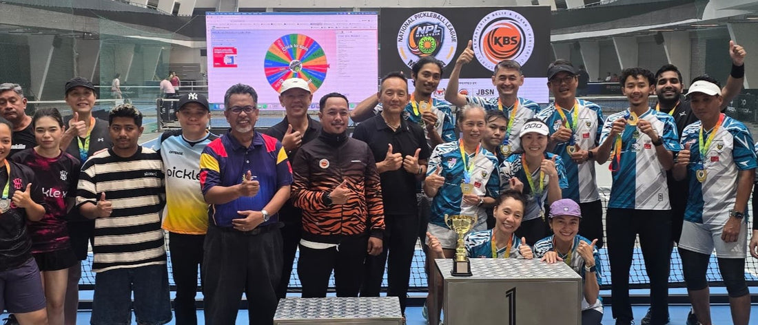 Players and guests pose with the trophy beneath screens showing the NPL Malaysia and KBS logos