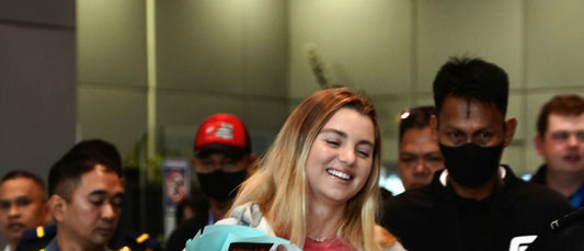 Anna Leigh Waters, carrying a bouquet of pink roses through the arrivals area at NAIA.
