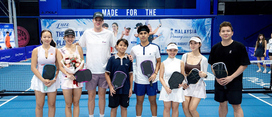 Sophia Tran Phuong Anh (left) poses with Luzz Pickleball players and staff in front of the Pickle By The Sea banner.